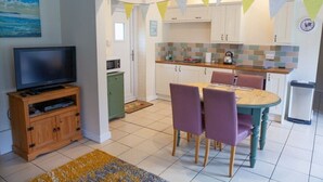 A compact living space with a dining area, kitchenette, and a television.