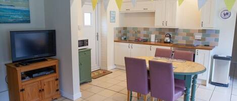 A compact living space with a dining area, kitchenette, and a television.