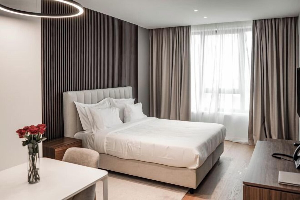 Una habitación de hotel moderna con una cama grande, un escritorio y un televisor.