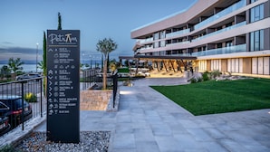 Un hotel moderno con un cartel que enumera servicios como recepción, piscina en el jardín y bistró.