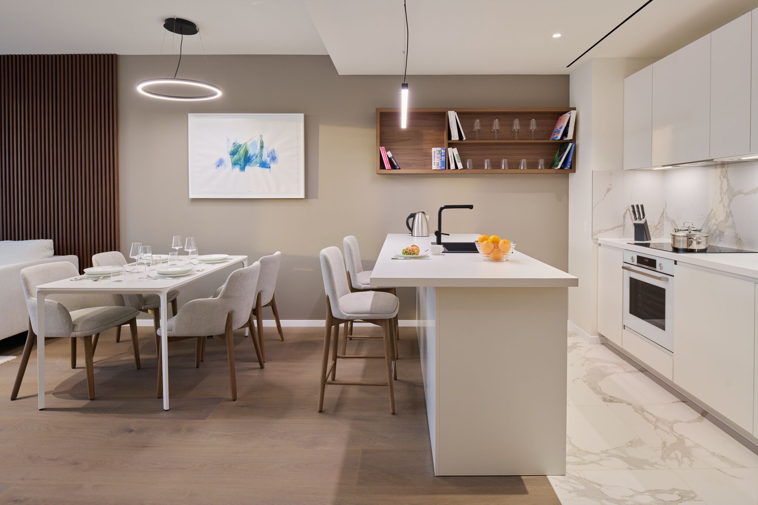 A modern kitchen with a central island, white cabinetry, and a dining area with a table and chairs.