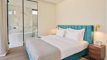 A modern bedroom with a teal upholstered headboard, a white bedspread, and a wooden nightstand with a box labeled "GREEN Modern Art".