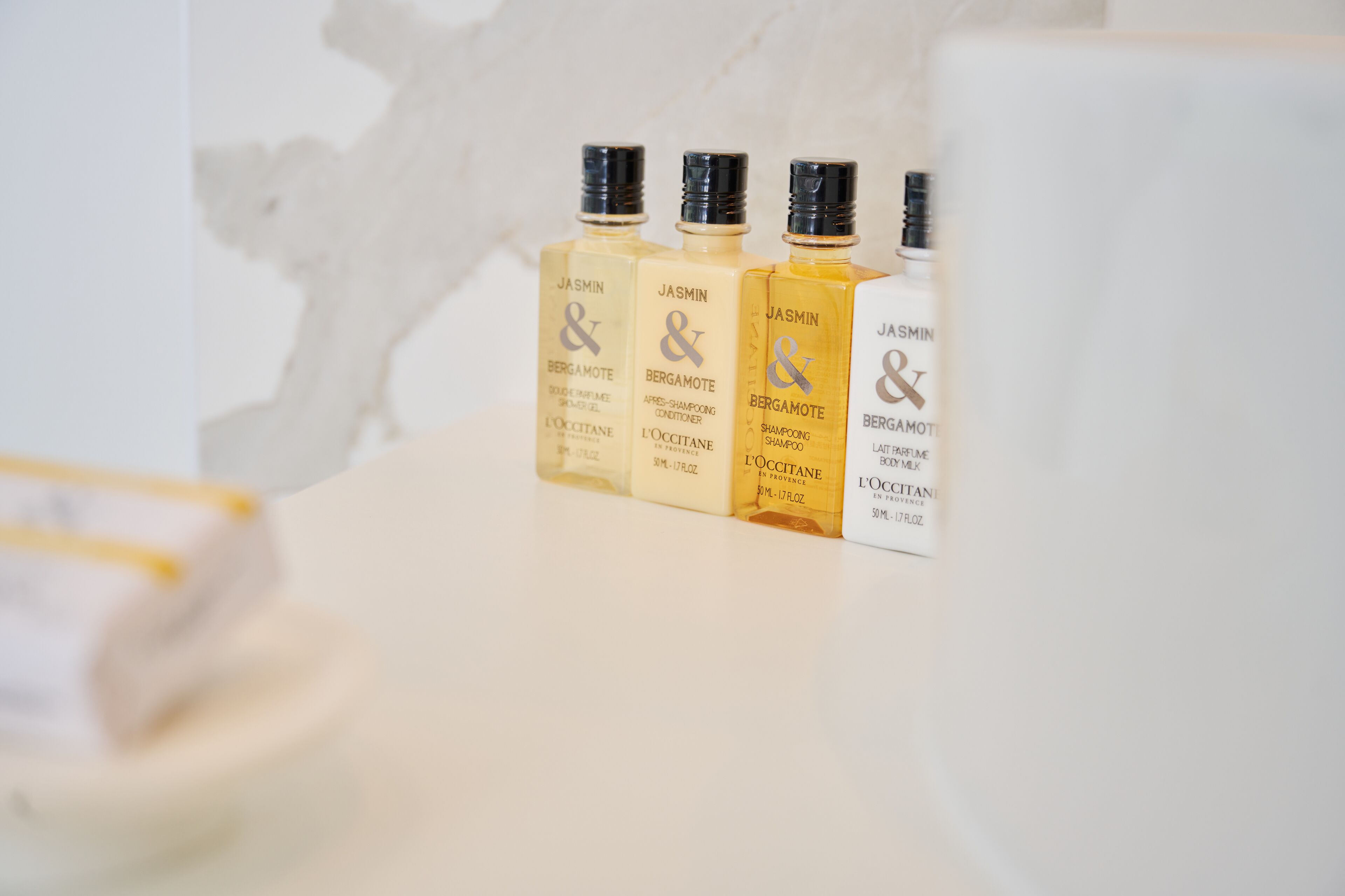 Quatre flacons de cologne au parfum de jasmin et de bergamote, posés sur une surface blanche.