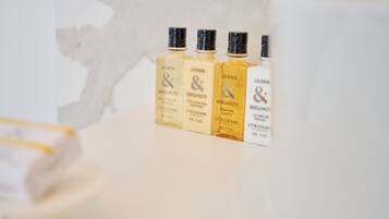 Quatre flacons de cologne au parfum de jasmin et de bergamote, posés sur une surface blanche.