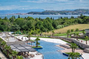Un resort con una piscina grande, mobiliario exterior y vista al mar.