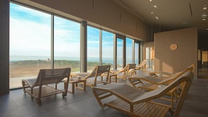 Una habitación iluminada por el sol con ventanas amplias, sillones de madera y vista al océano.