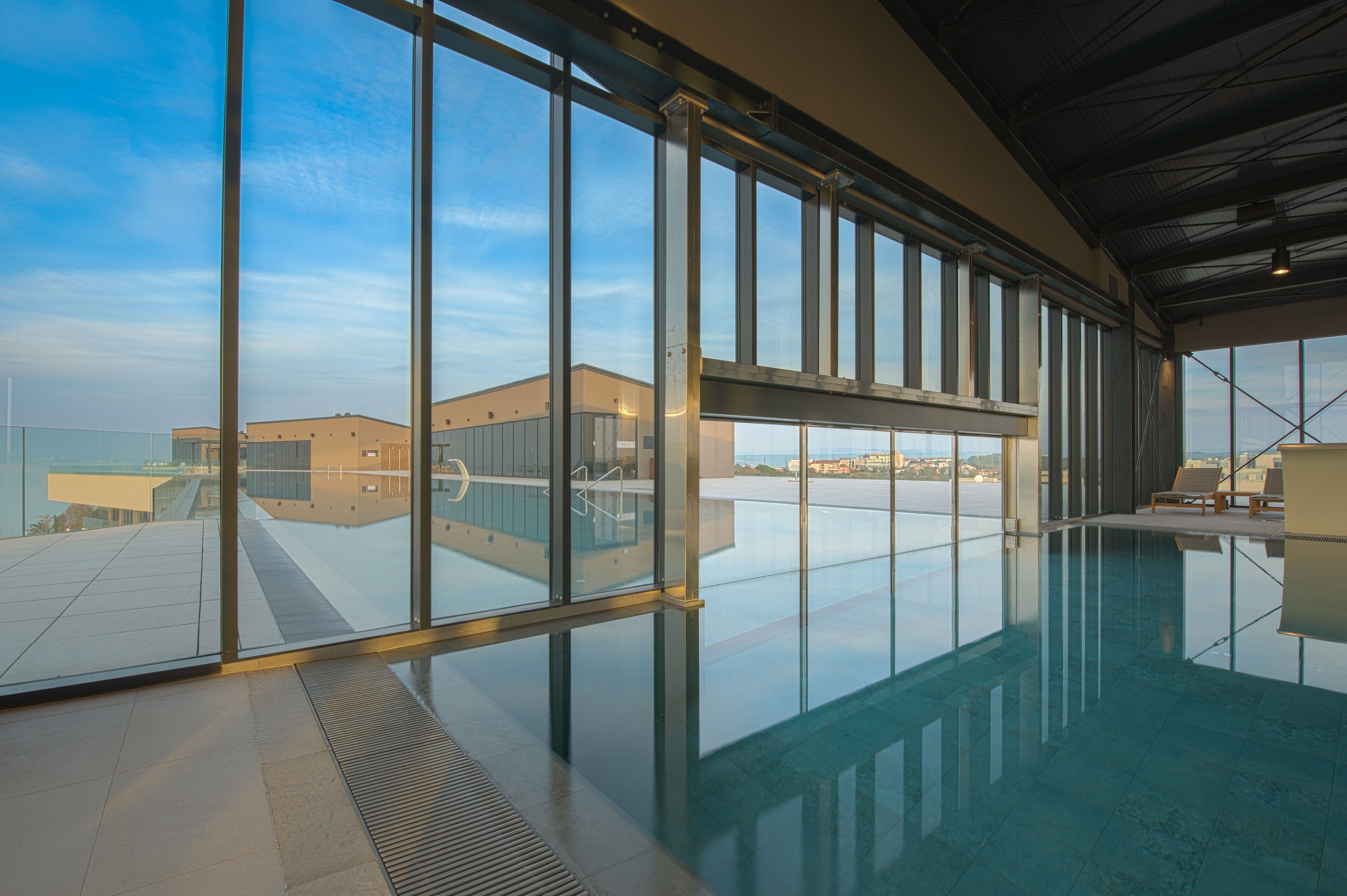 Una piscina interior moderna con grandes ventanales y vistas a edificios.