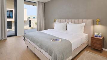 A modern bedroom with a large bed, a nightstand, a magazine, and a view of the outside.