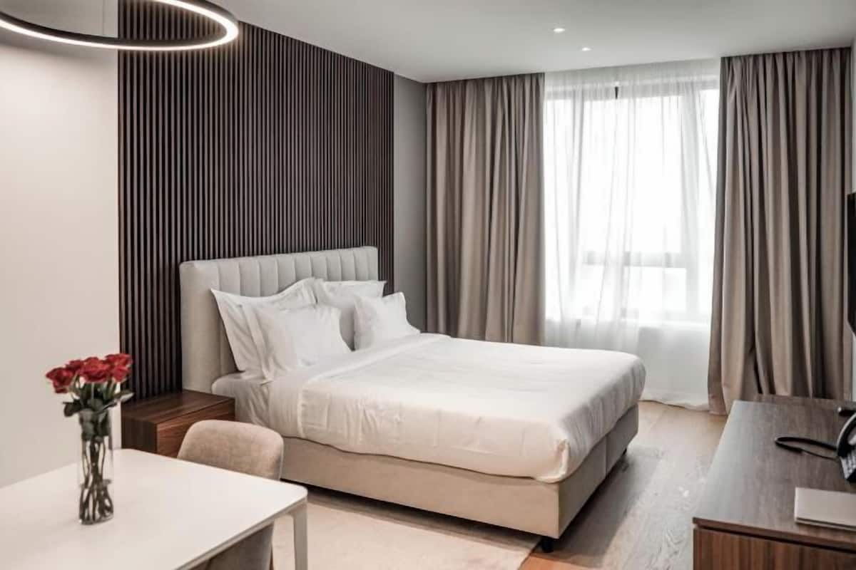 A modern hotel room with a large bed, a desk, and a TV.