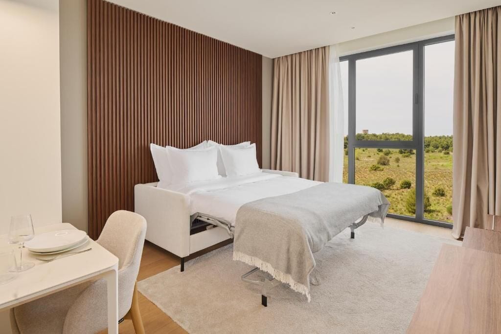 Une chambre moderne avec un lit, un bureau et une vue sur l’extérieur.
