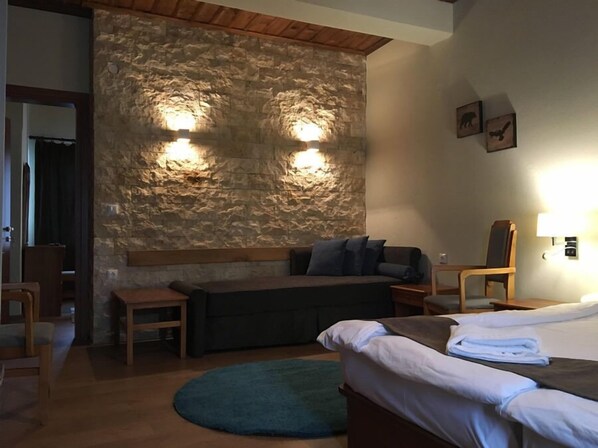 Una habitación acogedora con pared de piedra, una cama, un sofá y una silla.