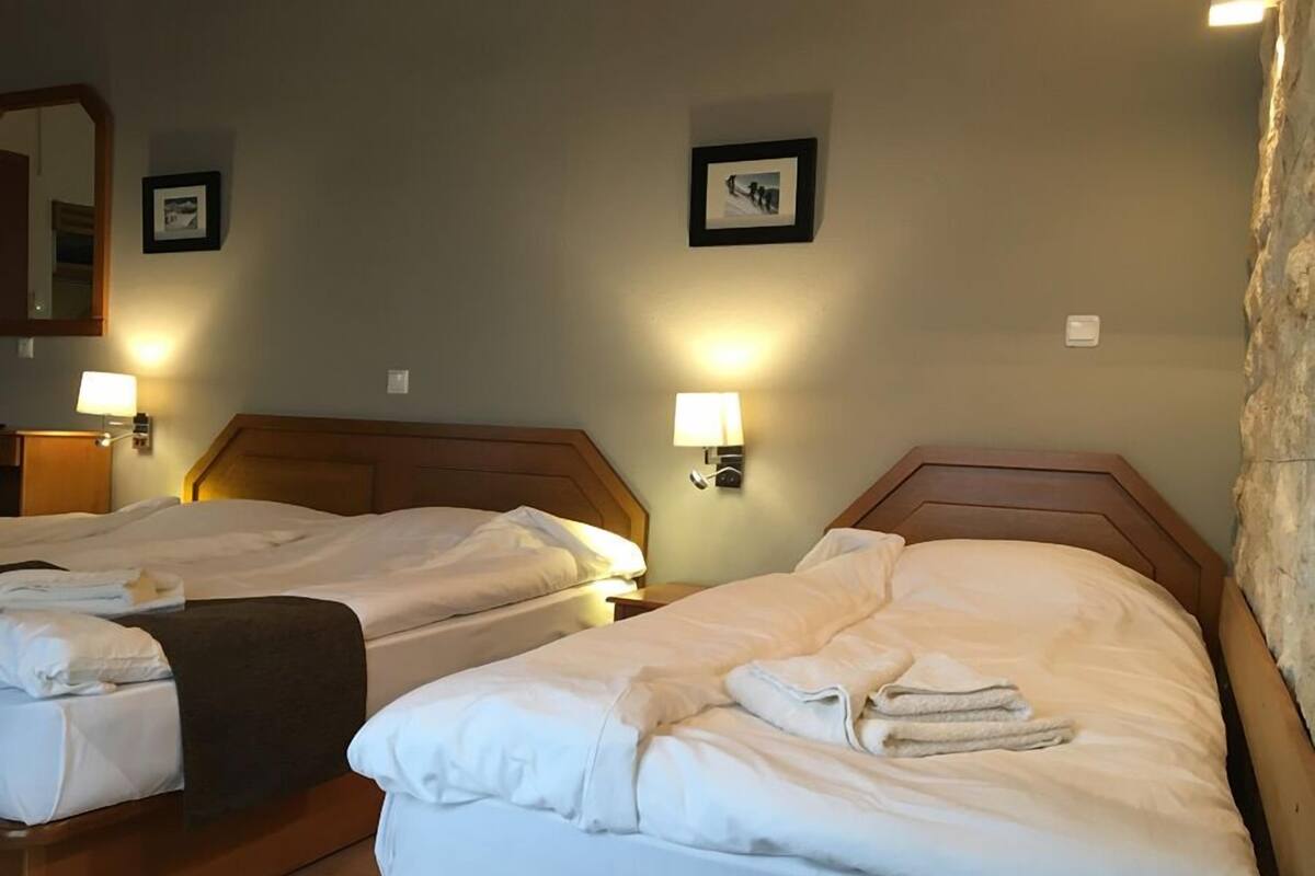 Two single beds with wooden headboards, white linens, and bedside lamps.