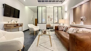 Een moderne woonkamer met een flatscreen televisie, een bank, een fauteuil en een salontafel.