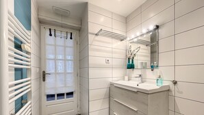 Een moderne badkamer met een wit wastafelmeubel, een spiegel met verlichting, een handdoekhouder en een toilet.