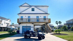 Une maison à deux étages avec un garage, un balcon et une allée permettant de garer une voiturette de golf.