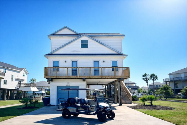 A two-story house with a garage, a balcony, and a driveway with a golf cart.