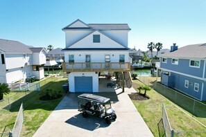 A two-story house with a covered garage, a small pool, and a golf cart parked in front.