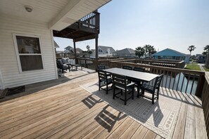 A wooden deck with a table and chairs, overlooking a body of water.
