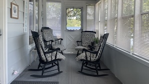 Eine Veranda mit zwei Schaukelstühlen, einem Schild mit der Aufschrift 'Relax' und einem Schild mit der Aufschrift 'Welcome'.