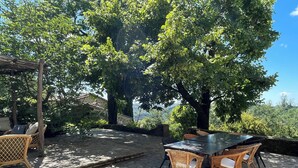 Eine Terrasse im Freien mit Steinböden, Korbmöbeln und Blick auf eine Berglandschaft.