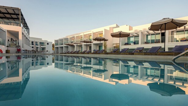 Een modern hotel met een zwembad, ligbedden en parasols.