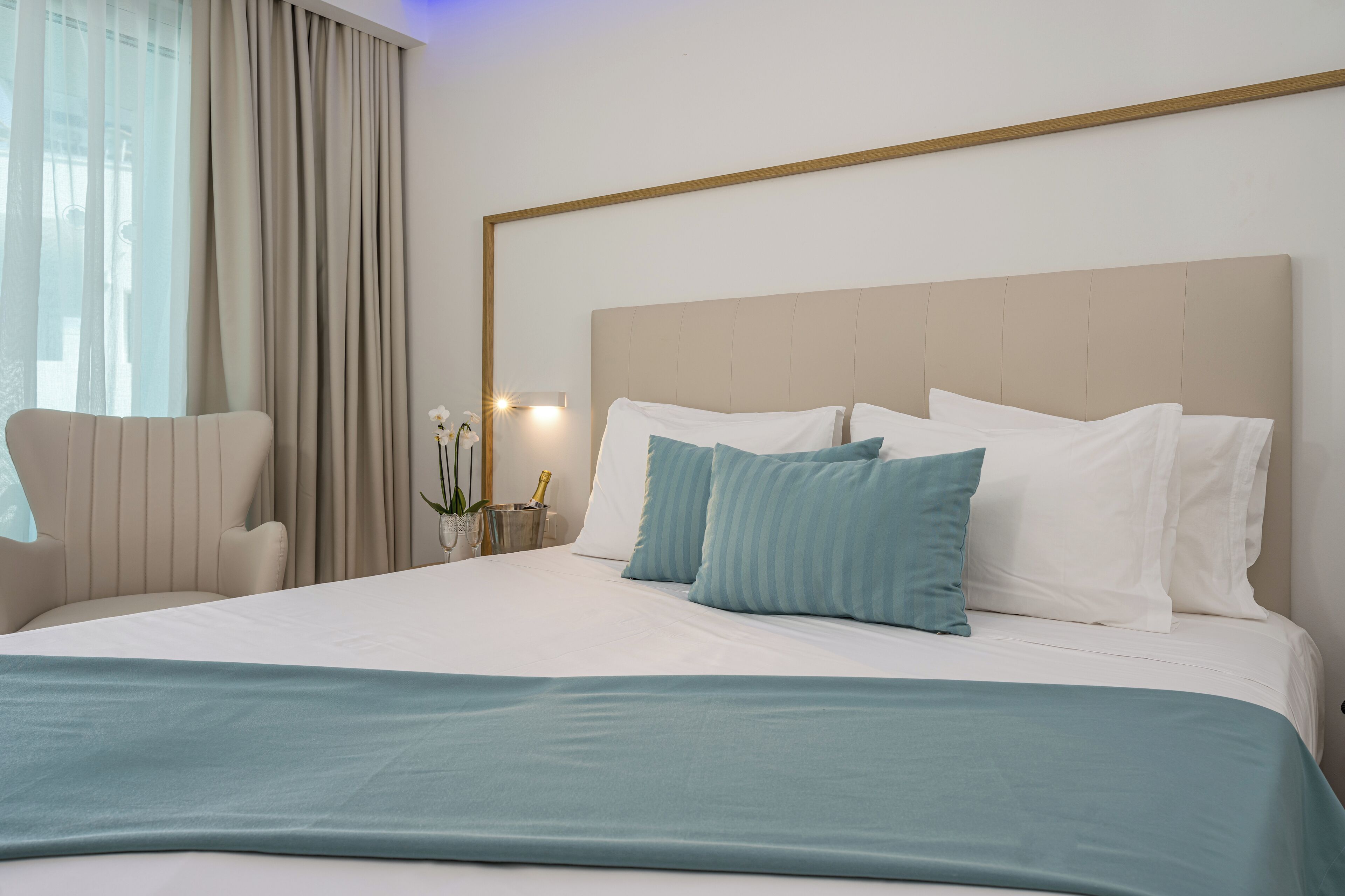 A hotel room with a large bed, a chair, and a window with curtains.