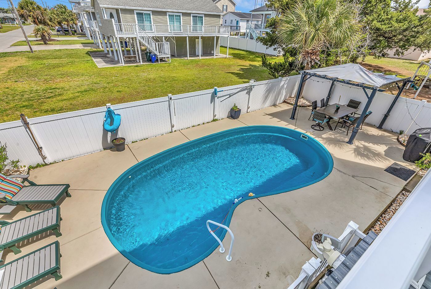 Ein Wohngrundstück mit Swimmingpool, überdachter Terrasse und einem Haus im Hintergrund.