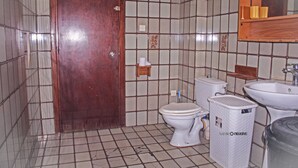 Een badkamer met toilet, wastafel en afvalbak.