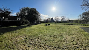 A grassy field with a clear sky and a bright sun. - Tumbleweed Cottage (Newark)