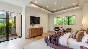 Une chambre moderne avec un grand lit, une télévision, une armoire en bois et un balcon doté de portes vitrées.