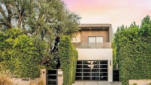 Un bâtiment moderne à deux étages, doté d’un garage et entouré d’une végétation luxuriante.