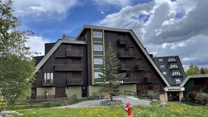 A modern building with a sloped roof, multiple balconies, and a fire hydrant in the foreground. - Apartment sleeps 6 All comforts, at the foot of the slopes (Montclar)