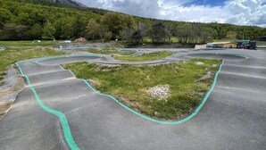 A mountain biking track with green markings, surrounded by grassy areas and trees, under a partly cloudy sky. - Apartment sleeps 6 All comforts, at the foot of the slopes (Montclar)