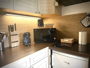Une cuisine équipée d’un four à micro-ondes, d’une machine à café et d’un grille-pain, le tout posé sur le plan de travail.