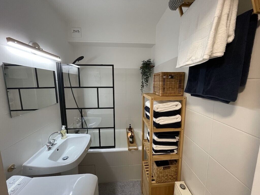 A bathroom with a sink, mirror, and a shelf with towels.