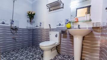 Un baño con inodoro, lavamanos, ducha y barra para toallas.