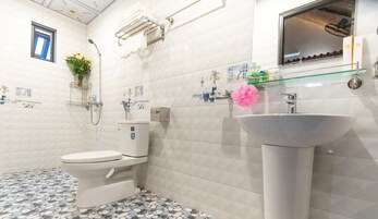 A bathroom with a toilet, a sink, a shower, and a small window.