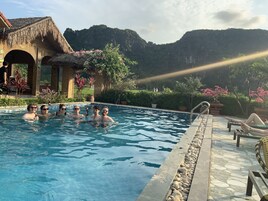 A swimming pool with clear water, surrounded by a stone deck and potted plants.