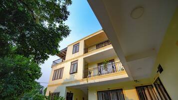 A multi-story building with balconies, a staircase, and a garden area.