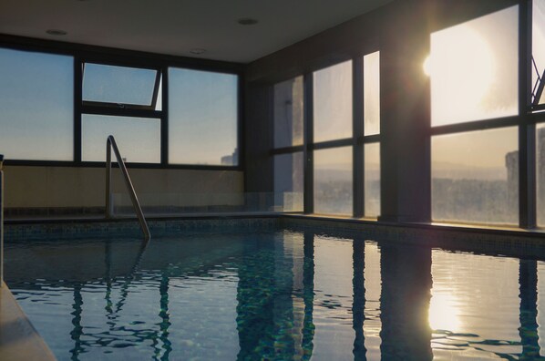 Una piscina cubierta, una piscina al aire libre, sombrillas, tumbonas