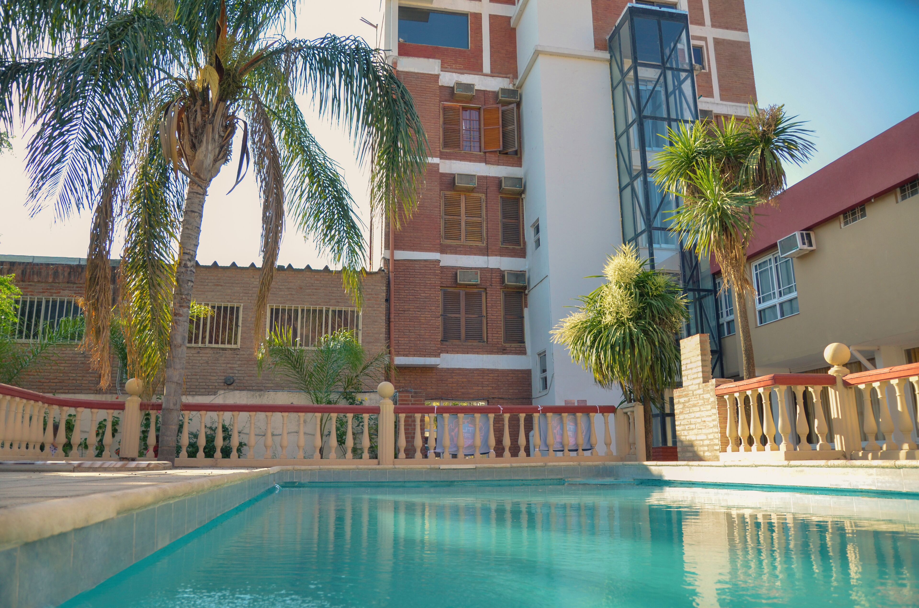 Una piscina techada, una piscina al aire libre, sombrillas