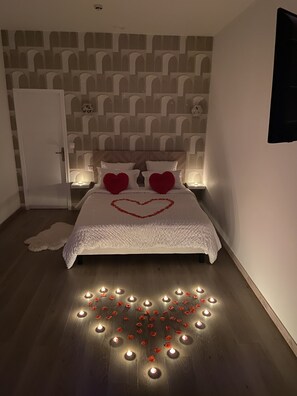 Un dormitorio con cama, decoración en forma de corazón sobre la cama y una pared con diseño estampado.