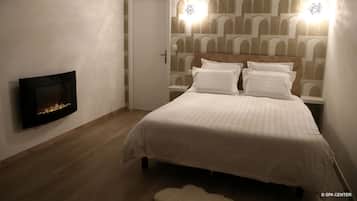 A bedroom with a bed, a wall-mounted fireplace, and patterned wallpaper.