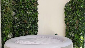 A round, white inflatable pool in a room with a wall covered in green foliage. - SPA CENTER Saint-Quentin (Saint-Quentin)