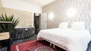A modern bedroom with a bed, a large mirror, a black and white vanity, a red patterned rug, and a geometric wall design. - SPA CENTER Saint-Quentin (Saint-Quentin)