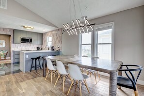 A modern kitchen with a central island, bar stools, and a dining table with chairs.