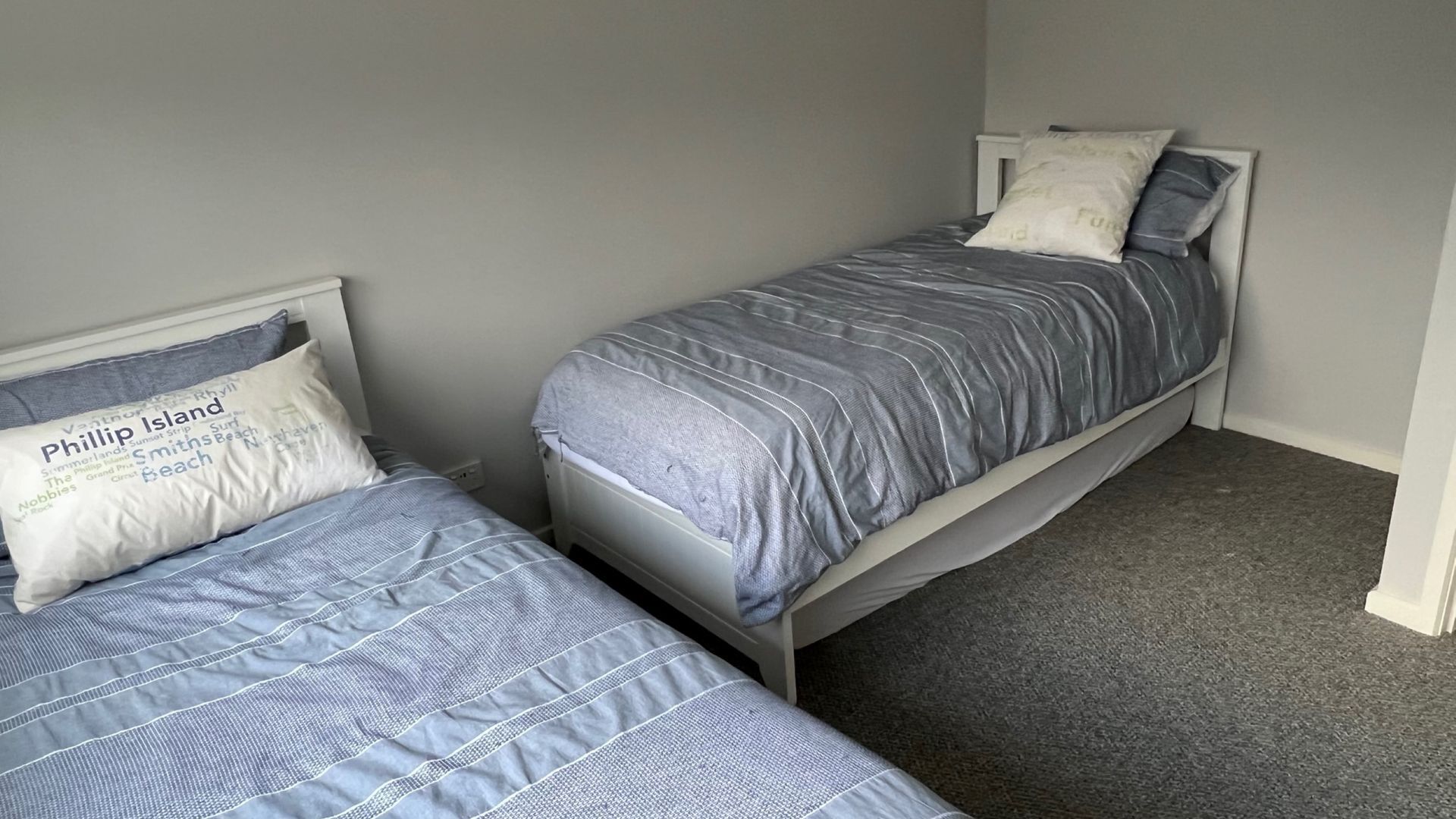 A bedroom with two single beds, each with a headboard and a pillow with text.