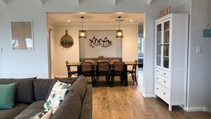 A modern living room with a gray sofa, a dining area with a wooden table and chairs, and a white cabinet with glass doors. - Seabreeze At Shalfleet (Ventnor)