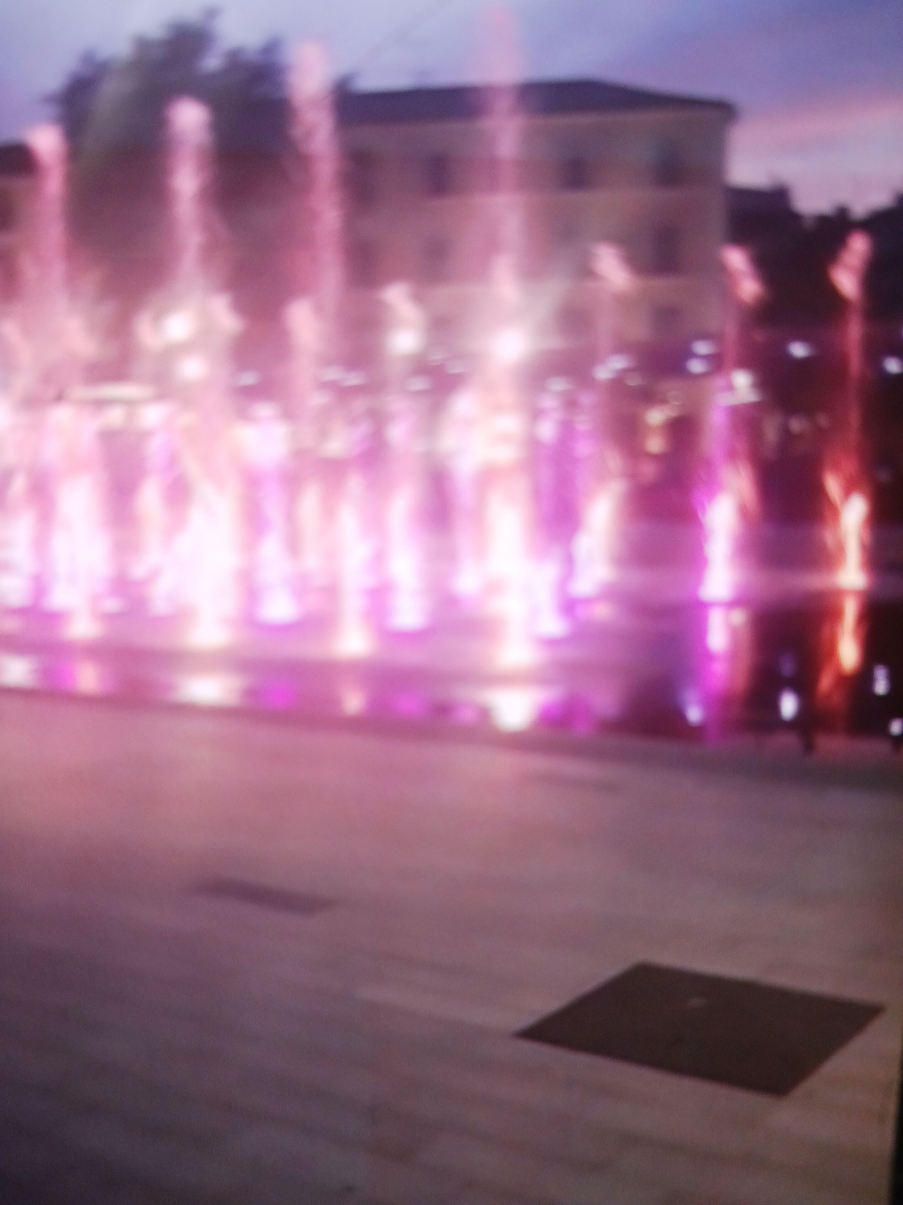 Una fuente con chorros de agua iluminados en luces moradas y rosadas.
