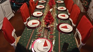 A dining table set for a meal with red and white plates, glasses, and napkins. A Christmas tree is visible in the background. - Appartement Centre Ville 110m2 (Béziers)